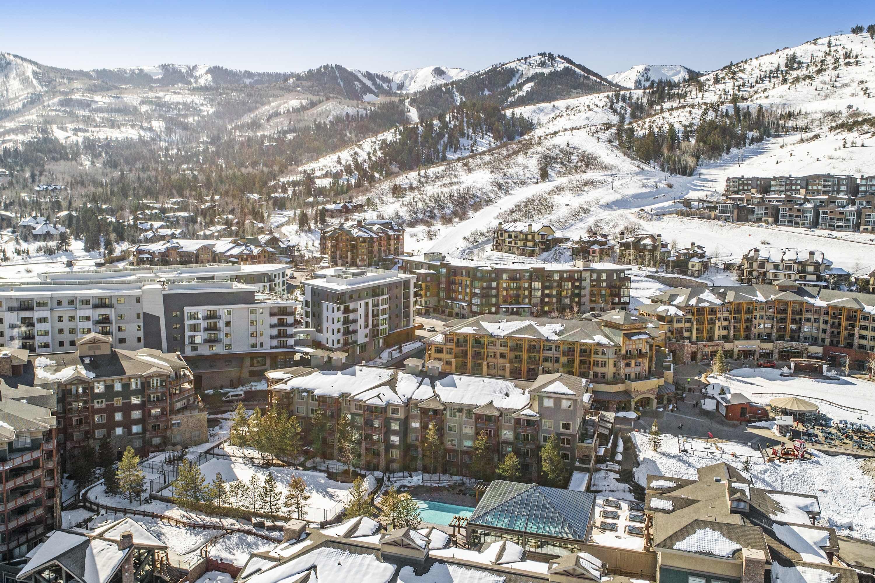 A resort with multiple buildings, a pool, and a ski slope in the background.