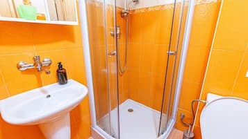 Et badeværelse med bruser, vask og toilet.