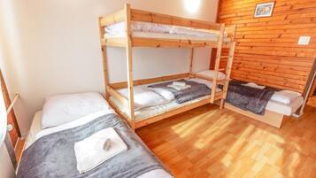 Une pièce avec deux lits superposés, un plancher en bois et un mur en bois.