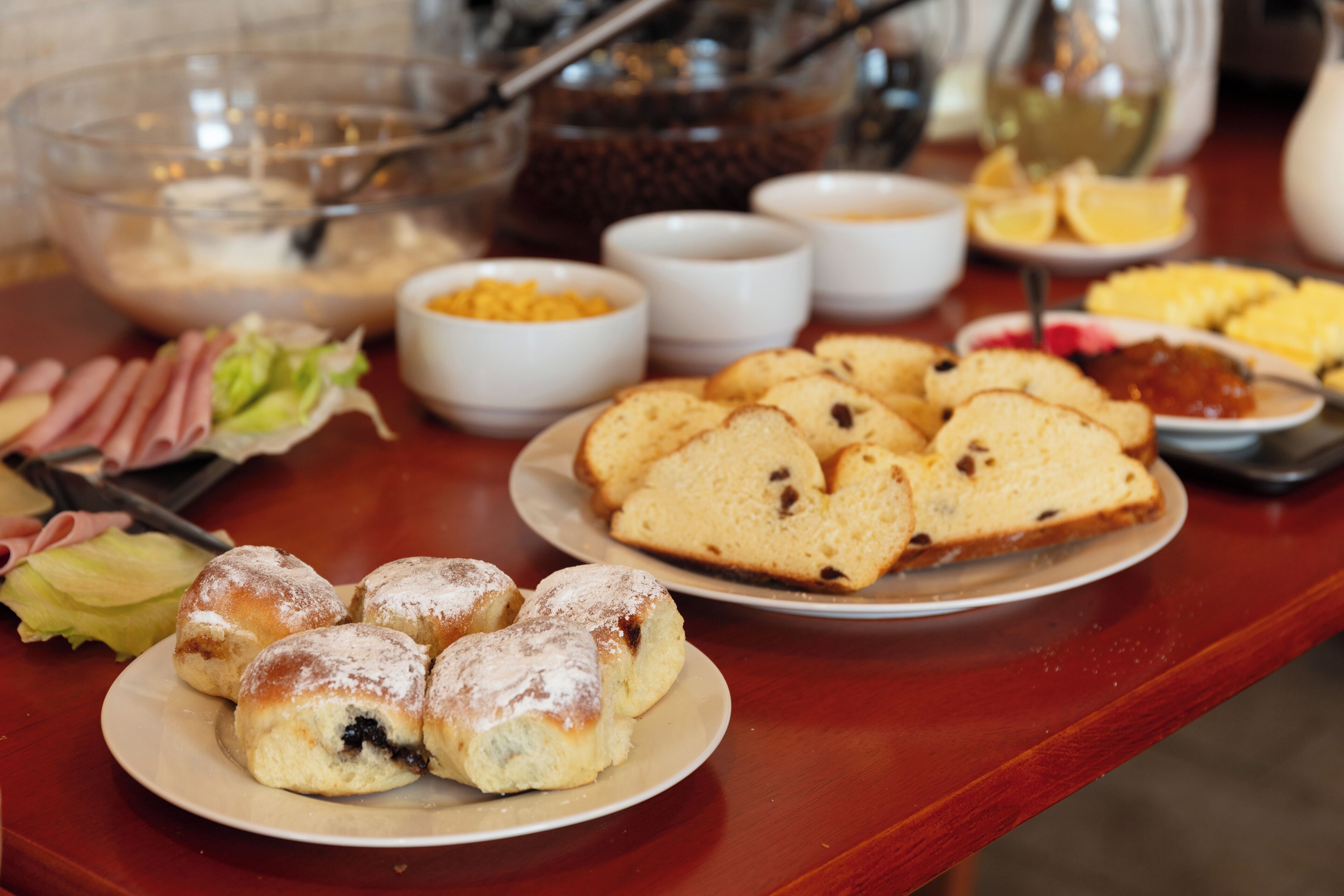 Ein Buffet mit verschiedenen Speisen, darunter Brot, Gebäck und Beilagen.