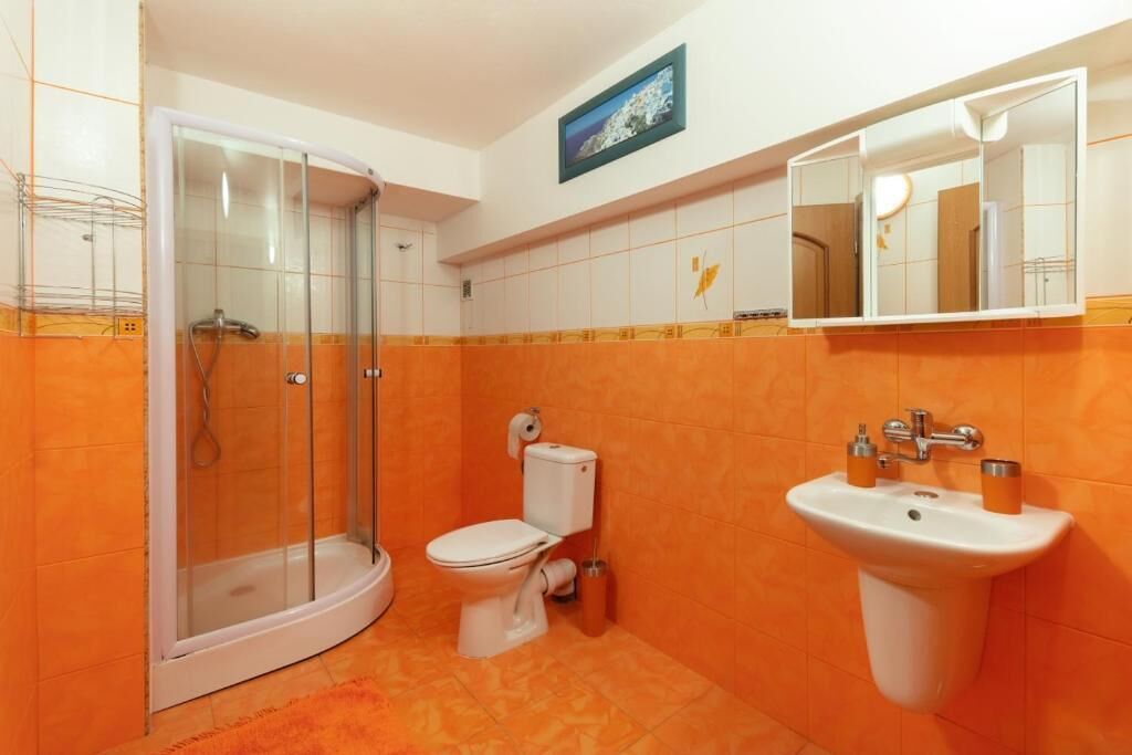 Un baño con cabina de ducha de vidrio, inodoro y lavamanos con espejo.