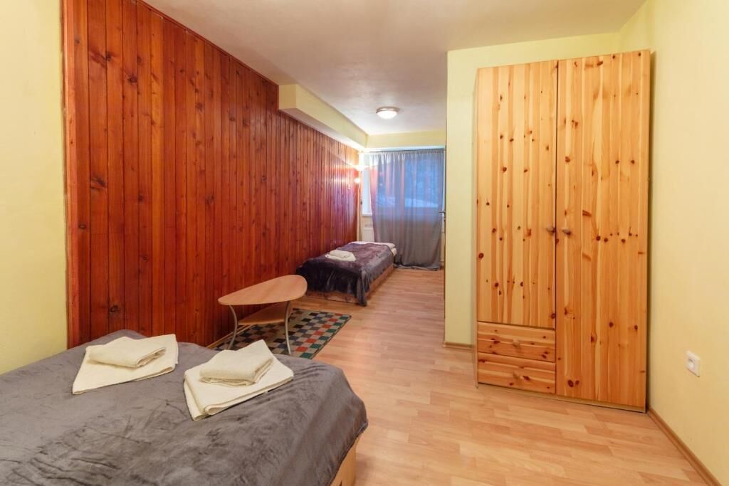 A room with wooden walls, a bed, a small table, and a wardrobe.