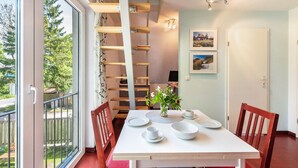 A dining area with a white table, chairs, and a staircase leading to an upper level.
