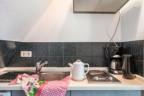 Une cuisine équipée d’un évier, d’une cuisinière, d’une bouilloire et d’une machine à café.