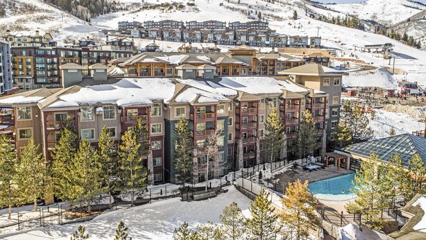 Ein mehrstöckiges Hotel mit Balkonen, einem Pool und einer Skipiste im Hintergrund.