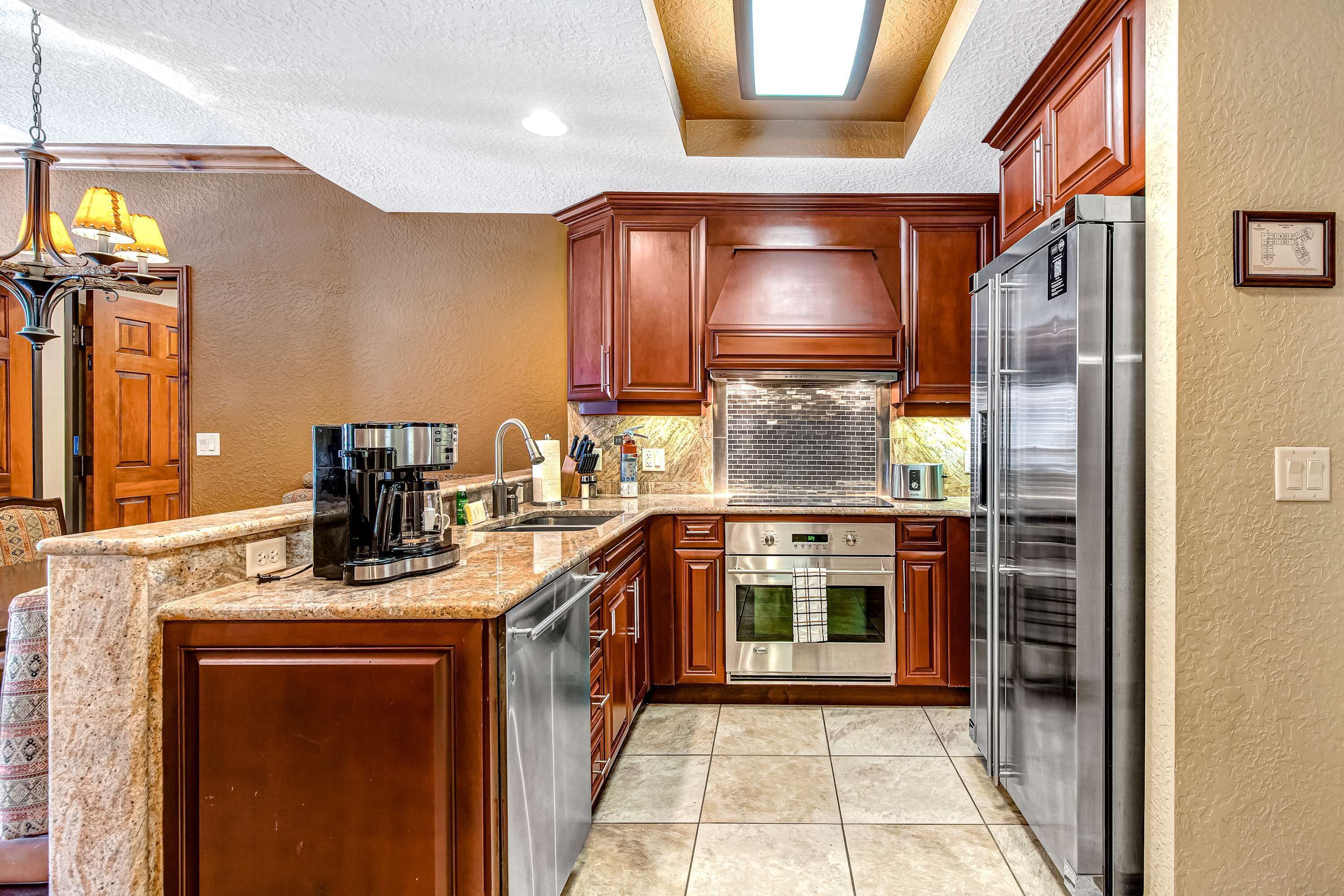A kitchen with wooden cabinets, stainless steel appliances, granite countertops, and a built-in oven.