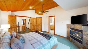 A bedroom with a bed, a television, a fireplace, and wooden doors. - Updated Condo minutes from downtown & slopes with  hot tub (Park City)