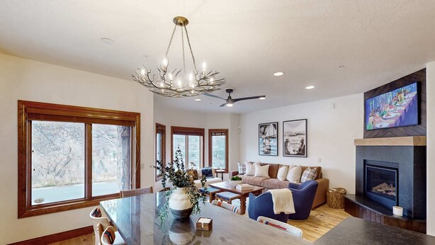 A modern kitchen with a large island, dining chairs, a chandelier, and a fireplace. - Updated Condo minutes from downtown & slopes with  hot tub (Park City)
