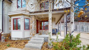 A two-story house with a stone facade, red-framed windows, and a stone staircase leading to the entrance. - Updated Condo minutes from downtown & slopes with  hot tub (Park City)