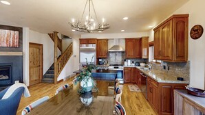 A spacious kitchen with wooden cabinets, a central island, and a chandelier. - Updated Condo minutes from downtown & slopes with  hot tub (Park City)