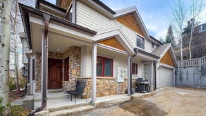 A two-story house with a stone facade, a covered porch, and a garage. - Updated Condo minutes from downtown & slopes with  hot tub (Park City)