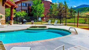 A swimming pool with a 'NO DIVING' sign, lounge chairs, and a house in the background. - Spacious mountain-view condo with fireplace, shared pool, hot tub & fitness room (Park City)