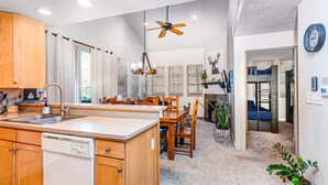 A modern kitchen with wooden cabinets, a built-in dishwasher, a central island, and a ceiling fan. - Spacious mountain-view condo with fireplace, shared pool, hot tub & fitness room (Park City)
