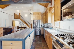 A spacious kitchen with wooden cabinets, a stainless steel refrigerator, a gas stove, and a large island with a sink. - Ski Lodge , Panoramic Views, Four Season Retreat (Park City)