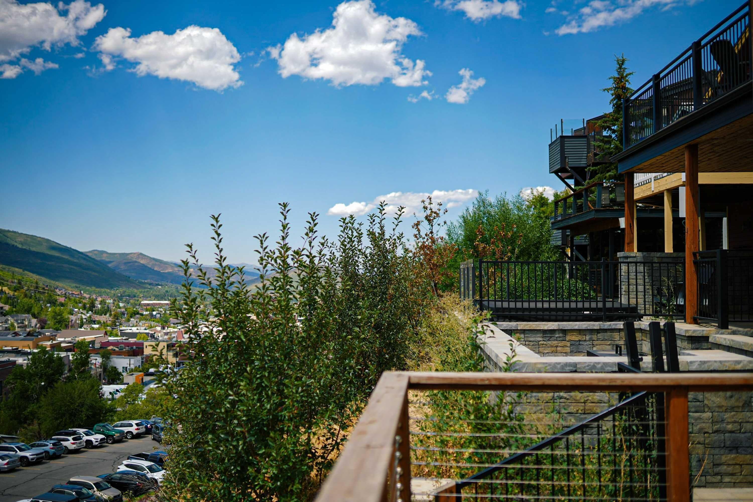 A view of a building with a balcony, a parking lot, and a mountainous landscape in the background.