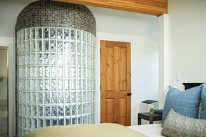 A bedroom with a bed, a wooden door, a small table with a lamp, and a glass block wall. - Ski Lodge , Panoramic Views, Four Season Retreat (Park City)