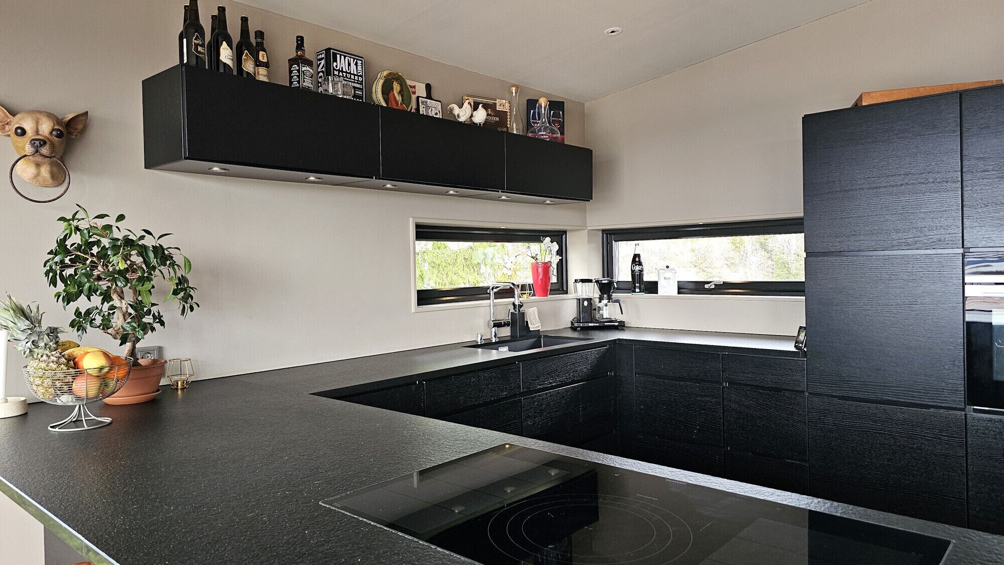 A modern kitchen with a black countertop, a built-in stove, and a window above the sink.