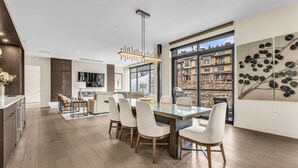 Una cocina moderna con comedor, ventanas amplias y vista a un edificio.