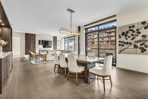 A modern kitchen with a dining area, large windows, and a view of a building. - Exclusive ski-in - ski-out Penthouse with Balcony & Gorgeous Slope Views (Park City)