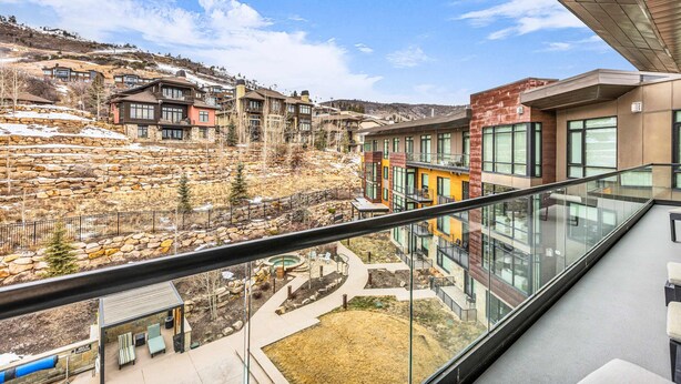 Un edificio moderno con ventanas amplias, un balcón y vistas a una zona montañosa.