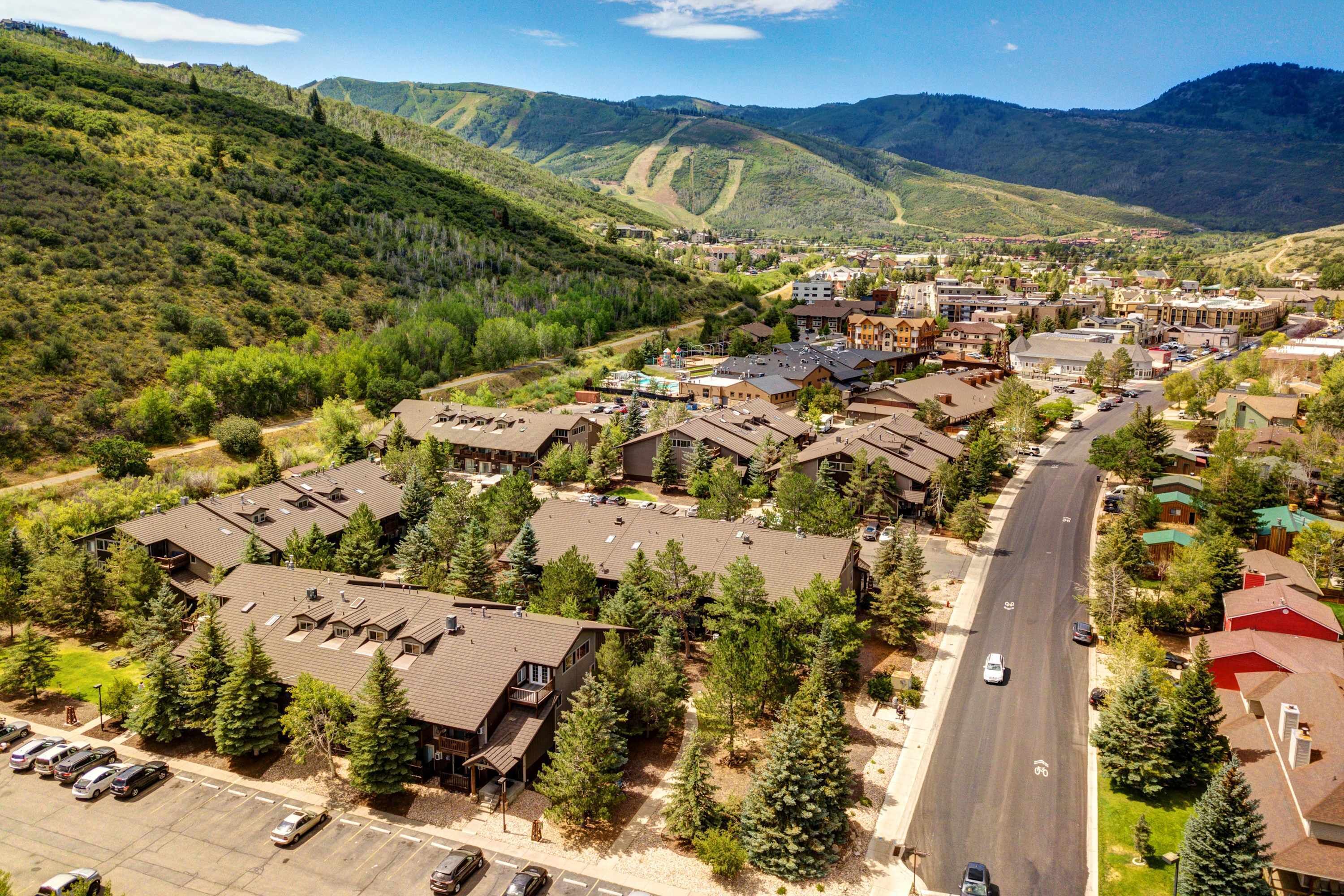 An aerial view of a town with a main road, buildings, and surrounding hills.