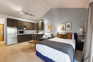 A modern hotel room with a large bed, a kitchenette, a dining area, and artwork on the walls. - Lovely studio in the heart of town with Pool & Hot Tub on-site, WiFi & deck (Park City)