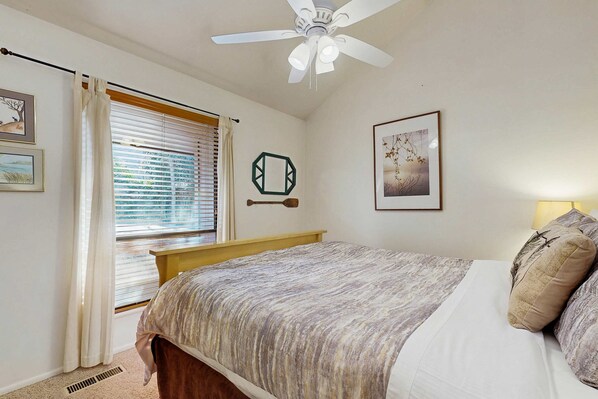 A bedroom with a bed, a ceiling fan, a window with blinds, and wall-mounted artwork. - Spacious ski getaway with private hot tub & game room -Close to little and big Cottonwood Canyons (Sandy)