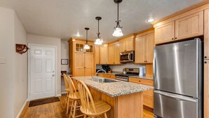 A kitchen with wooden cabinets, a stainless steel refrigerator, a microwave, and a granite countertop. - Terrific, central location for ski resort access with  private hot tub & fireplace (Cottonwood Heights)