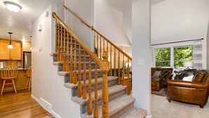 A staircase with wooden balusters, a kitchen with wooden cabinets and a refrigerator, and a living room with a leather sofa and a window. - Terrific, central location for ski resort access with  private hot tub & fireplace (Cottonwood Heights)