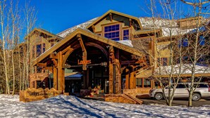 Un lodge in legno con un'ampia entrata, un cartello che riporta 'The Lodges at Deer Valley' e un paesaggio innevato.