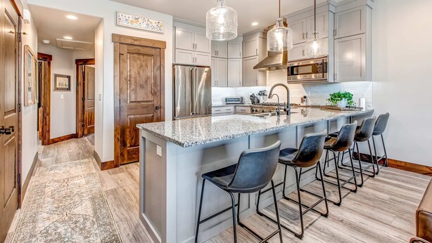 A modern kitchen with a central island, bar stools, stainless steel appliances, and pendant lighting. - Stunning dog-friendly mountain condo with hot tub, gas grill, & AC (Kamas)