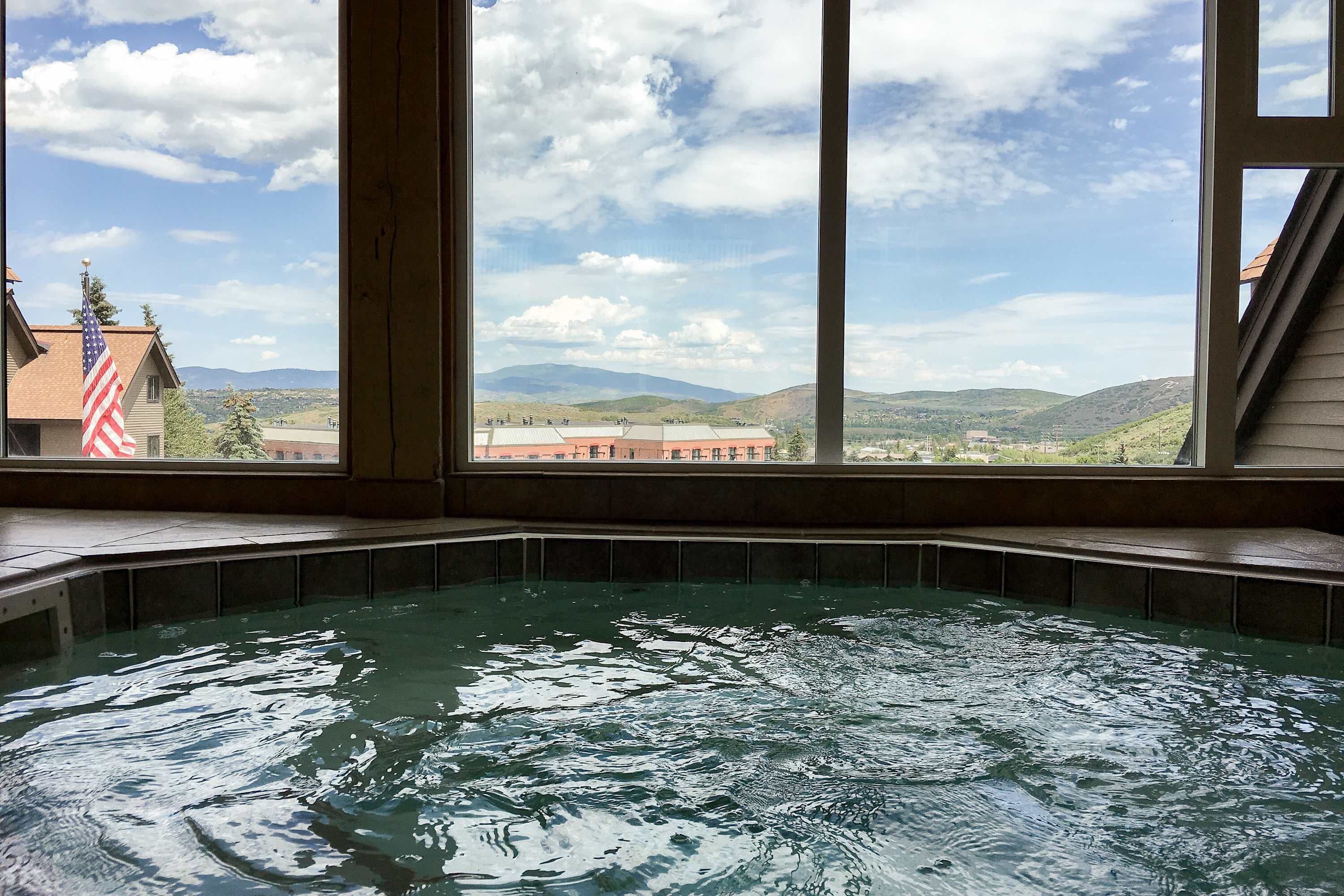 Un bain à remous avec vue sur les montagnes et un drapeau à l’extérieur.