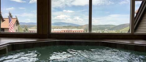 Un bain à remous avec vue sur les montagnes et un drapeau à l’extérieur.