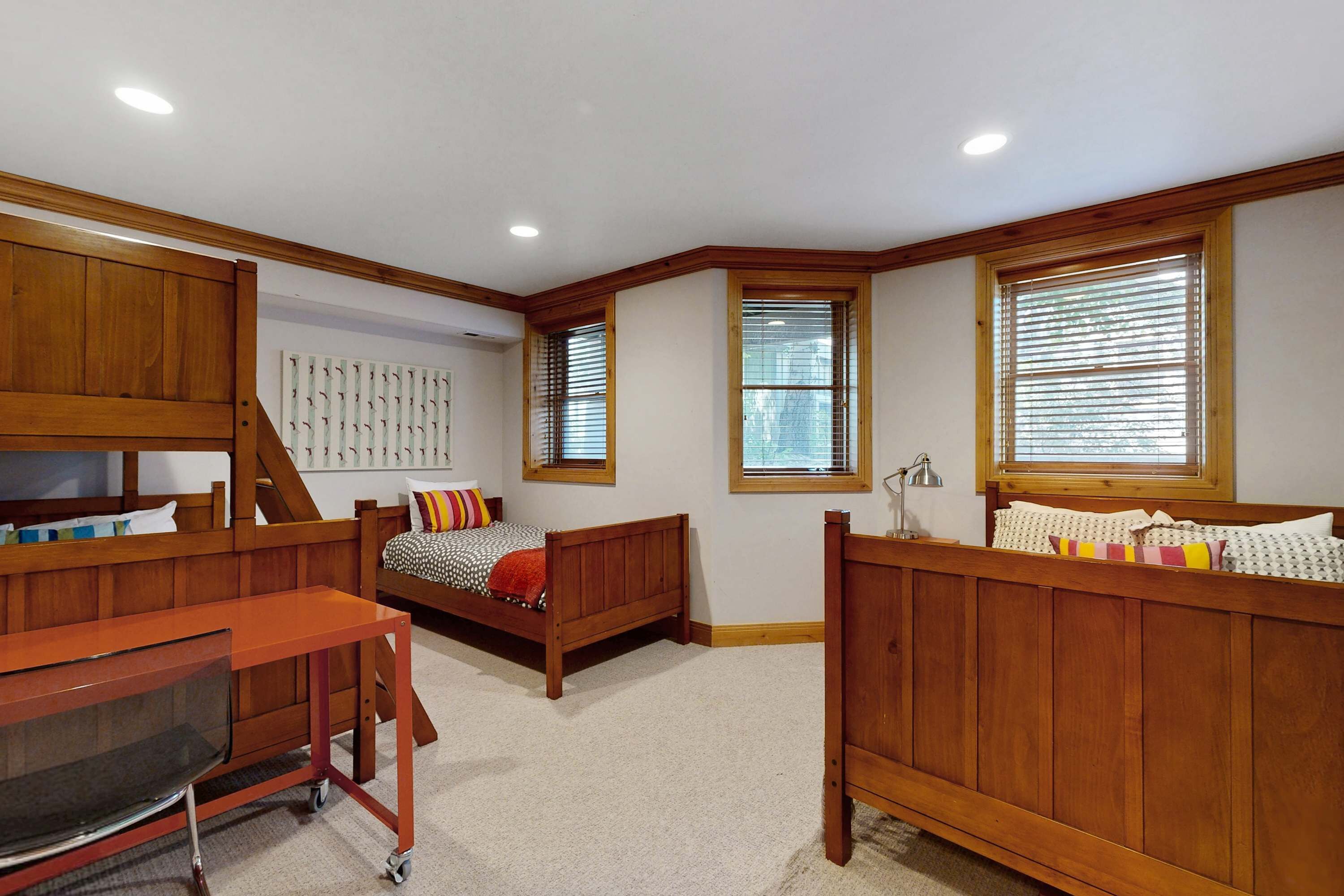 A bedroom with two wooden beds, a desk, and a chair.