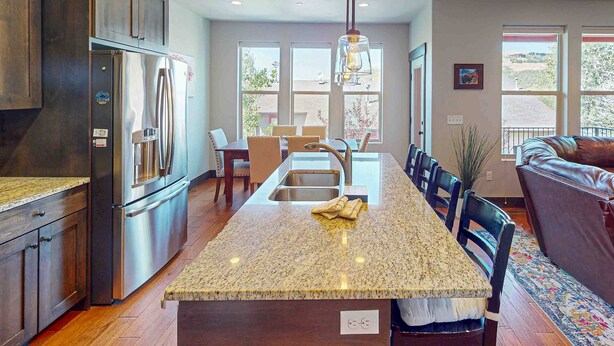 A kitchen with a central island, stainless steel appliances, and a dining area with a sofa. - Spacious townhome with pool, private hot tub & clubhouse - Dog Friendly (Kamas)