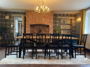 A dining area with a brick fireplace, wooden table, and chairs.