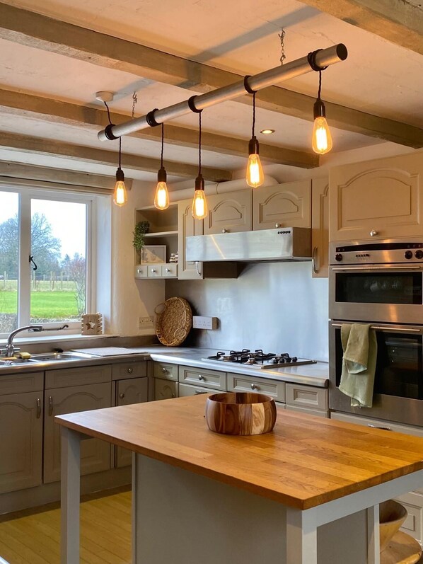 A kitchen with a central island, stainless steel appliances, and pendant lighting.