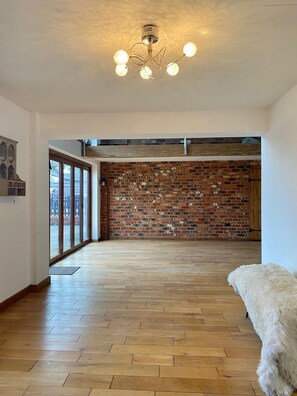 A spacious room with a wooden floor, a brick wall, and a ceiling light fixture.