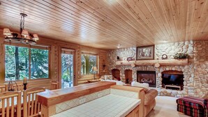 A wooden cabin interior with a stone fireplace, wooden furniture, and large windows. - Unbeatable mid-mountain condo in Silver Lake Village w/ shared pool & hot tub (Park City)