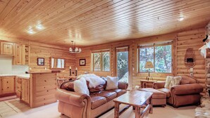 A log cabin interior with a leather sofa, wooden dining table, and a kitchen area. - Unbeatable mid-mountain condo in Silver Lake Village w/ shared pool & hot tub (Park City)
