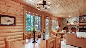 A wooden cabin interior with a dining table, chairs, a fireplace, and framed pictures on the walls. - Unbeatable mid-mountain condo in Silver Lake Village w/ shared pool & hot tub (Park City)