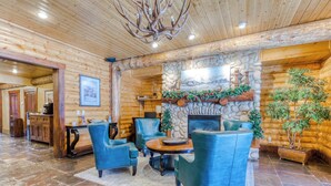 A log cabin interior with a stone fireplace, blue leather chairs, and a chandelier. - Unbeatable mid-mountain condo in Silver Lake Village w/ shared pool & hot tub (Park City)
