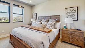 A bedroom with a bed, nightstands, a dresser, and artwork on the walls. - Lakeview Condo with fireplace, gas grill & W&D - close to skiing, hiking, & lake (Heber City)