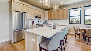 A modern kitchen with wooden cabinets, stainless steel appliances, and a central island with bar stools. - Lakeview Condo with fireplace, gas grill & W&D - close to skiing, hiking, & lake (Heber City)