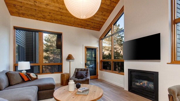 A modern living room with a fireplace, large windows, a flat-screen TV, and a cozy seating area. - Modern mountain escape with wonderful views, pool, hot tub-minutes to skiing (Park City)