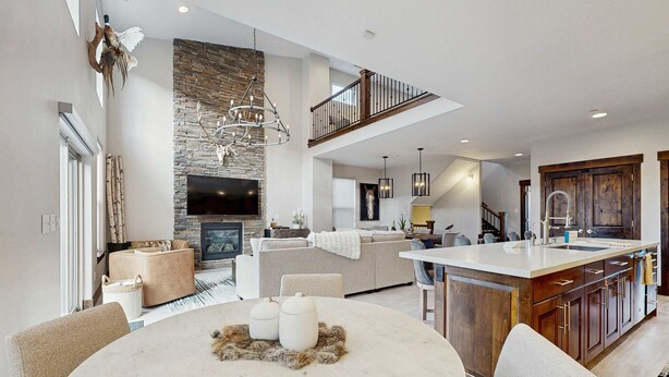 A spacious living area with a fireplace, a dining table, and a kitchen with a large island. - Three King Suites, 12 min to Deer Valley & Park City Resorts (Kamas)