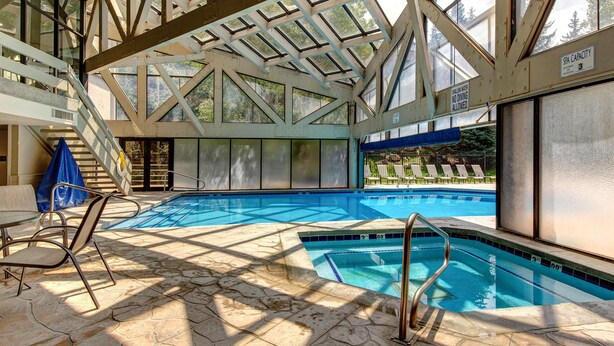 Uma piscina interior com teto de vidro, piscina azul e cadeira de salva-vidas.