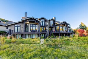 A modern multi-story house with a large balcony, a chimney, and a well-maintained lawn. - Luxury townhome on the golf course with 3 fireplaces, gas grill, & great view (Park City)