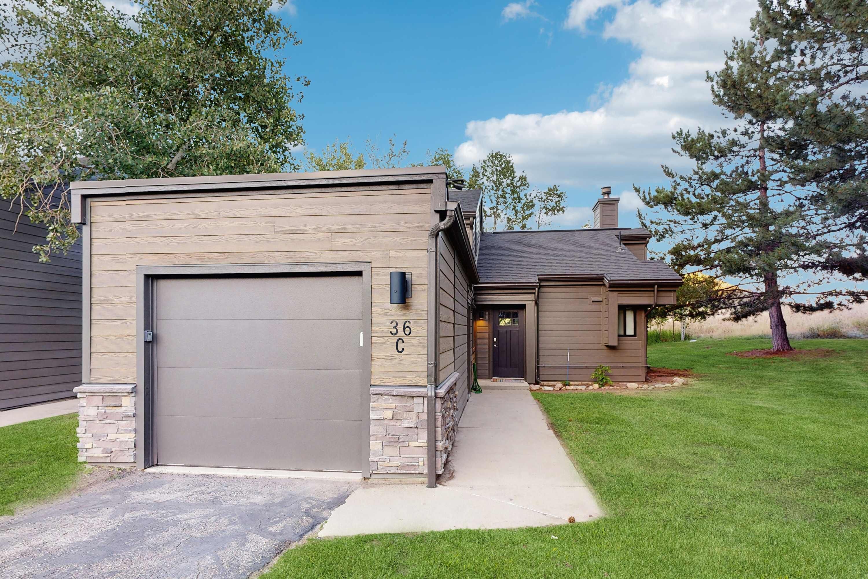 Un immeuble résidentiel doté d’un garage, d’un socle en pierre et du numéro « 36 C » inscrit sur le mur.