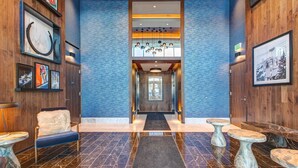 Eine Hotelhalle mit Marmorboden, Holzwänden, einer zentralen Treppe und einem Empfangstresen.